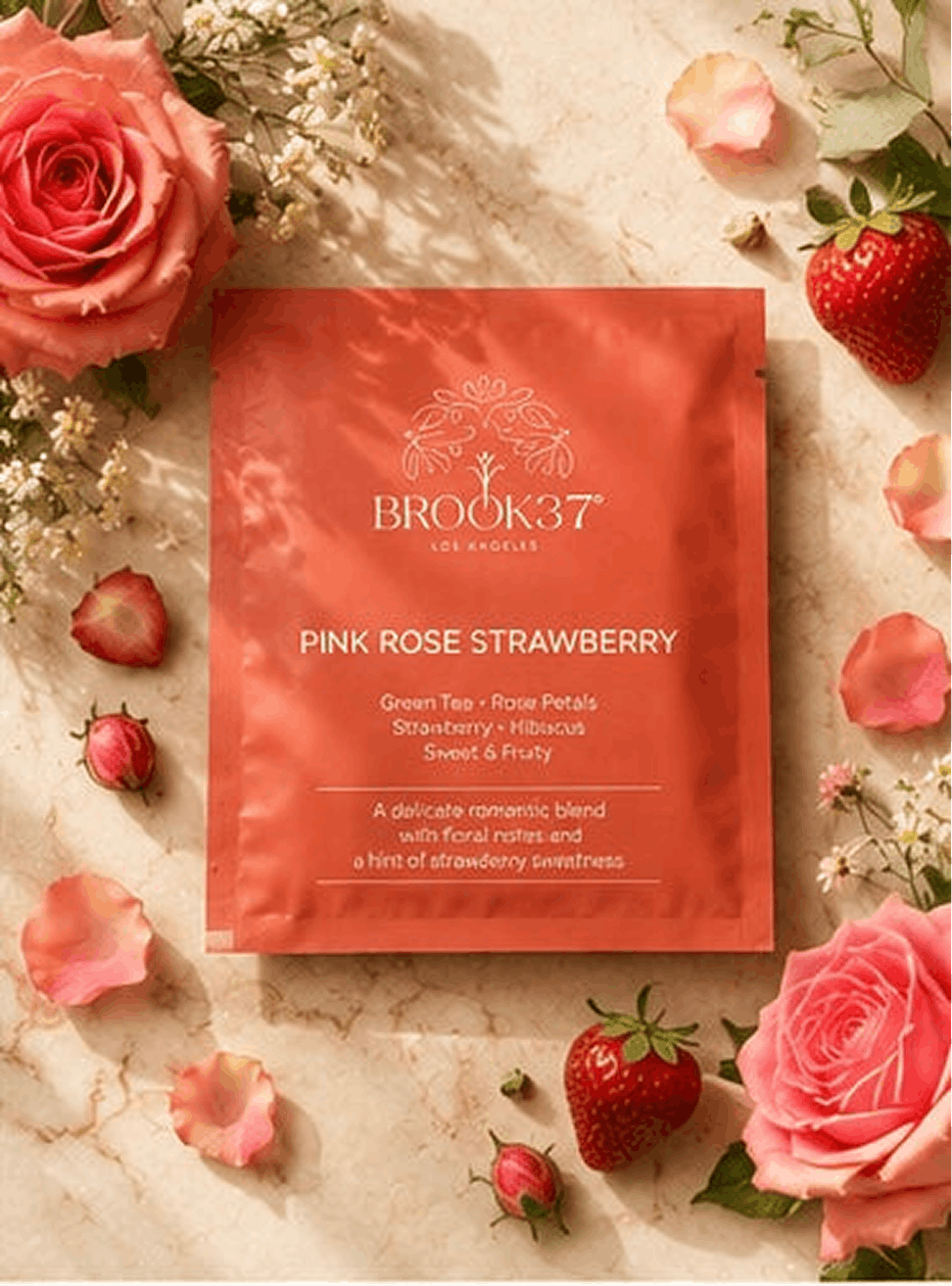 Brook37 pink rose strawberry product packaging surrounded by pink roses and strawberries on a marble surface.