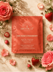 Brook37 pink rose strawberry product packaging surrounded by pink roses and strawberries on a marble surface.