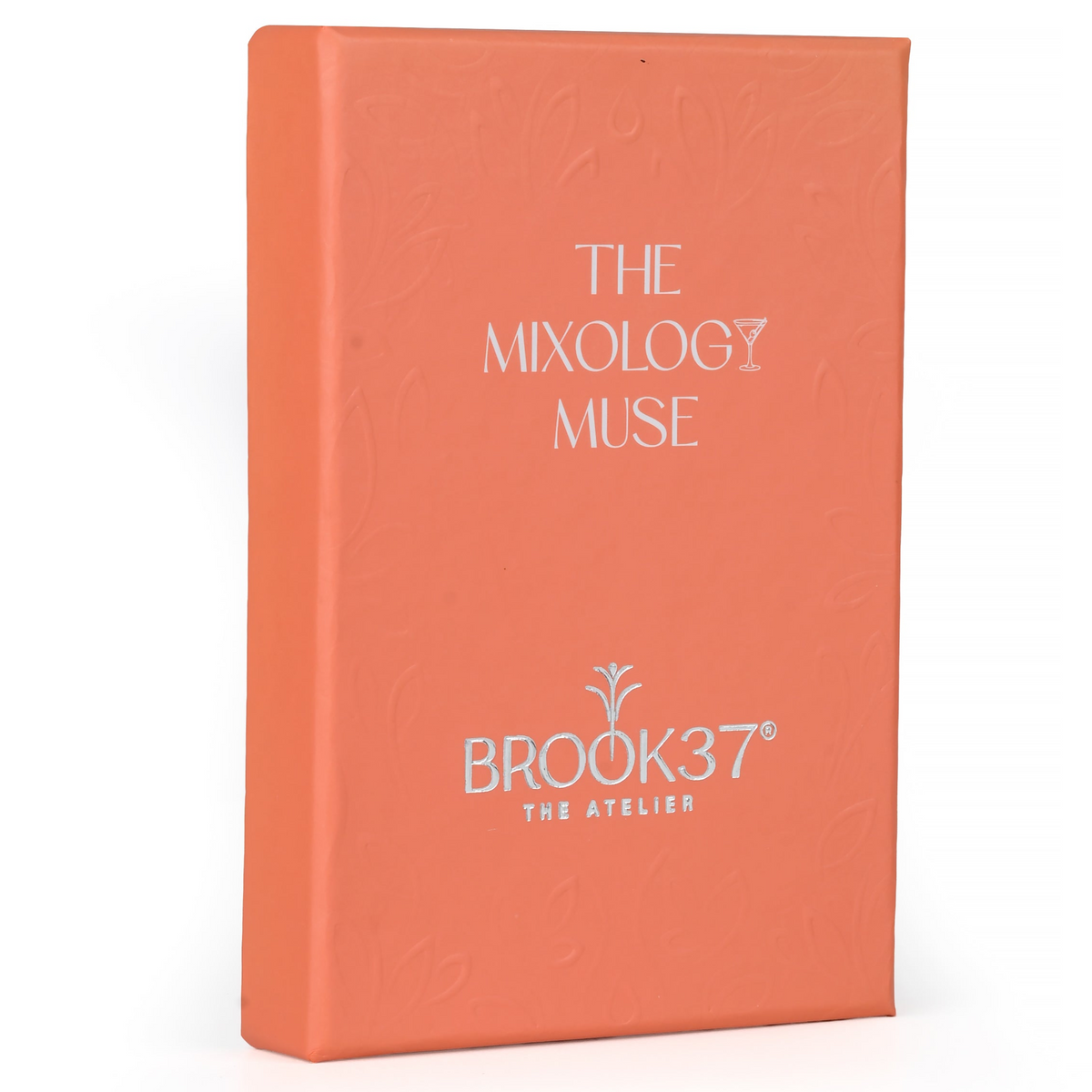 A coral hardcover box standing upright on a white background, featuring white printed text that reads 'THE MIXOLOGY MUSE' and 'BROOK37 THE ATTELIER'.