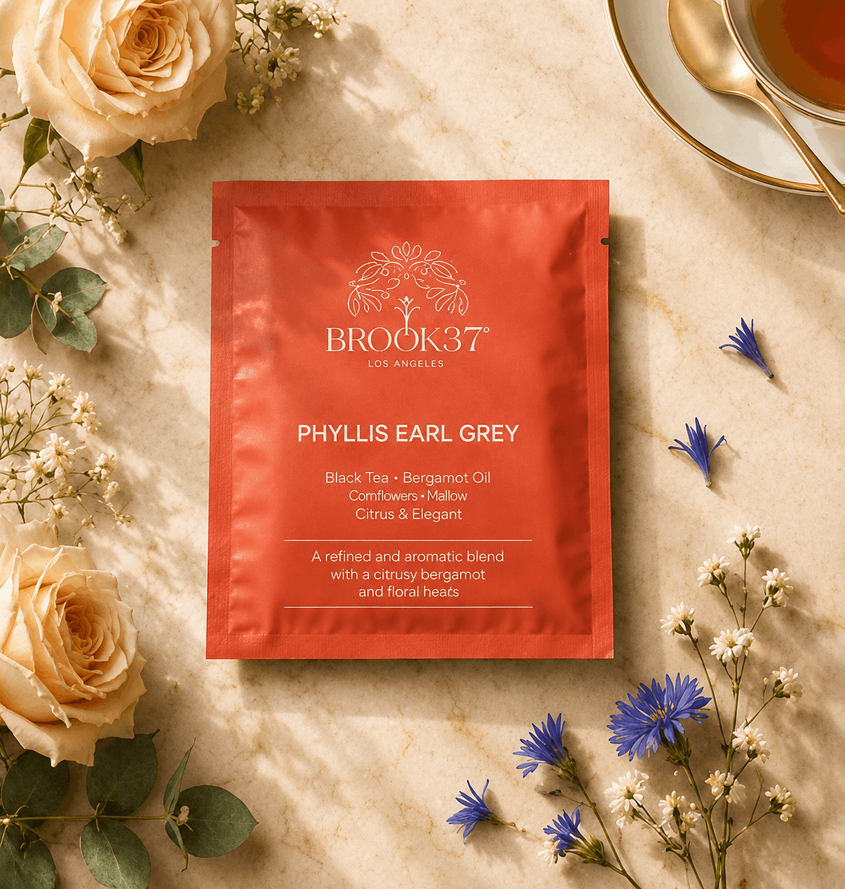 Brook37 Phyllis Earl Grey tea bag on a marble surface with flowers and a cup of tea.
